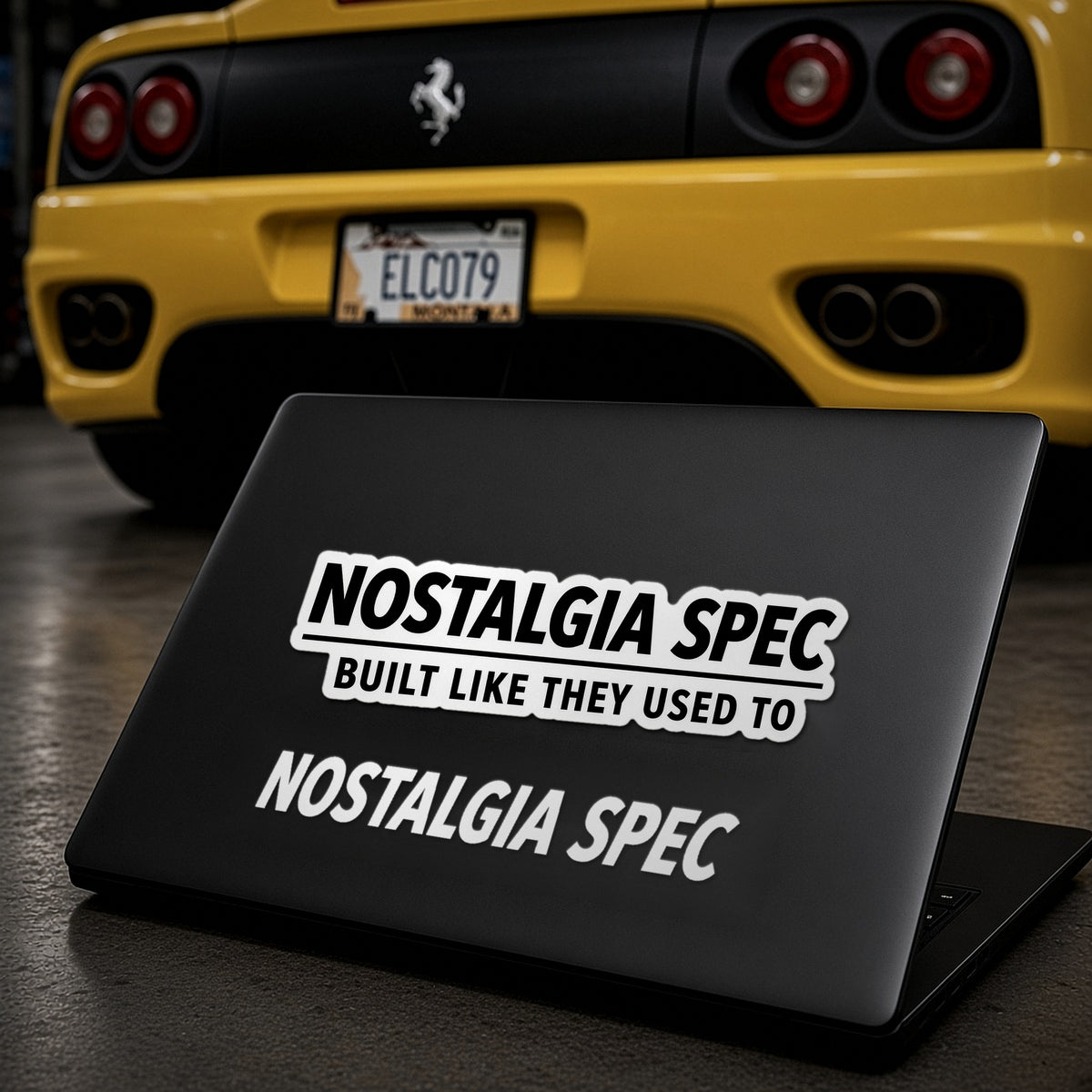 Nostalgia Spec stickers on a matte black laptop lid in front of a yellow Ferrari 360